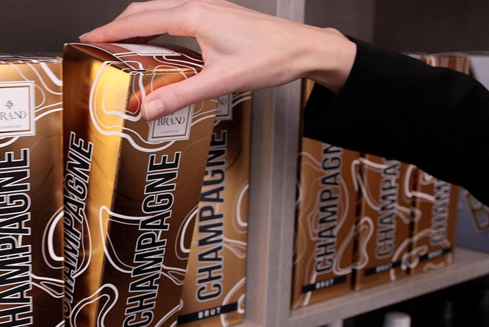 Champagne packaging with cold foil, being taken from a shelf